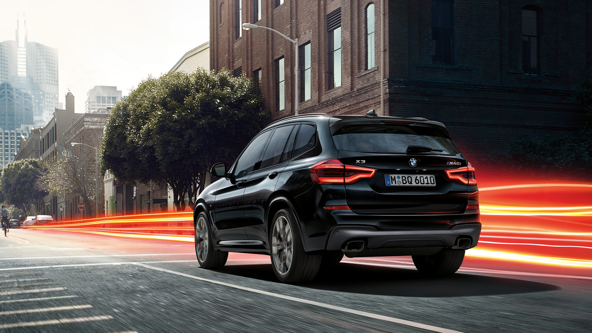 BMW X3 M40i, háromnegyedes hátulnézet. Zafírfekete metálfényezésű BMW X3 M40i, menet közben, kívülről, háromnegyedes hátulnézetből, városi környezetben, fénycsíkokkal.