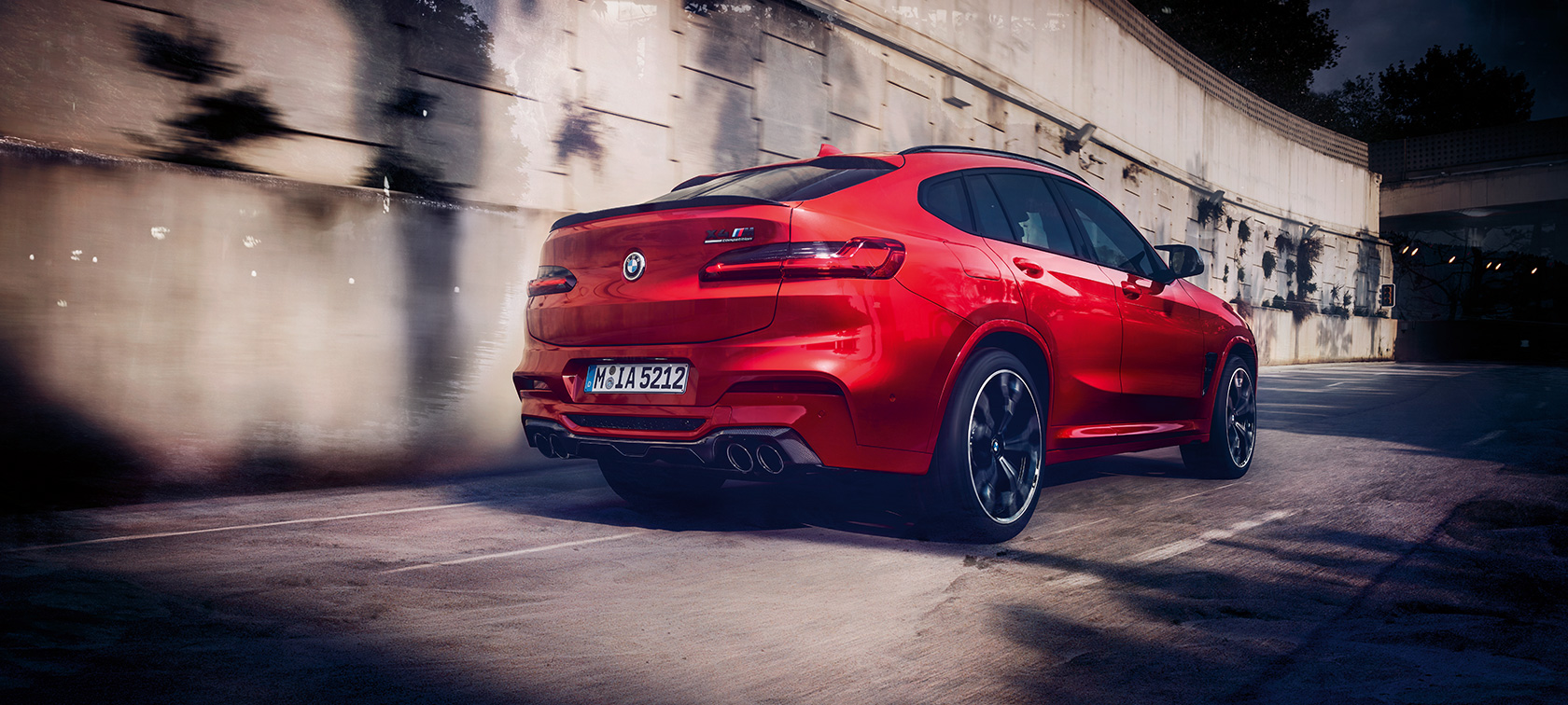 BMW X4 M Competition, háromnegyedes hátulnézet. Toronto metálfényezésű BMW X4 M Competition, menet közben, kívülről, háromnegyedes hátulnézetből.