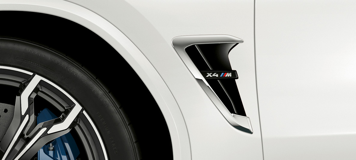 BMW X4 M, M kopoltyú. Alpesi fehér BMW X4 M, külső, M kopoltyúk krómozott elemekkel és típusfelirattal.