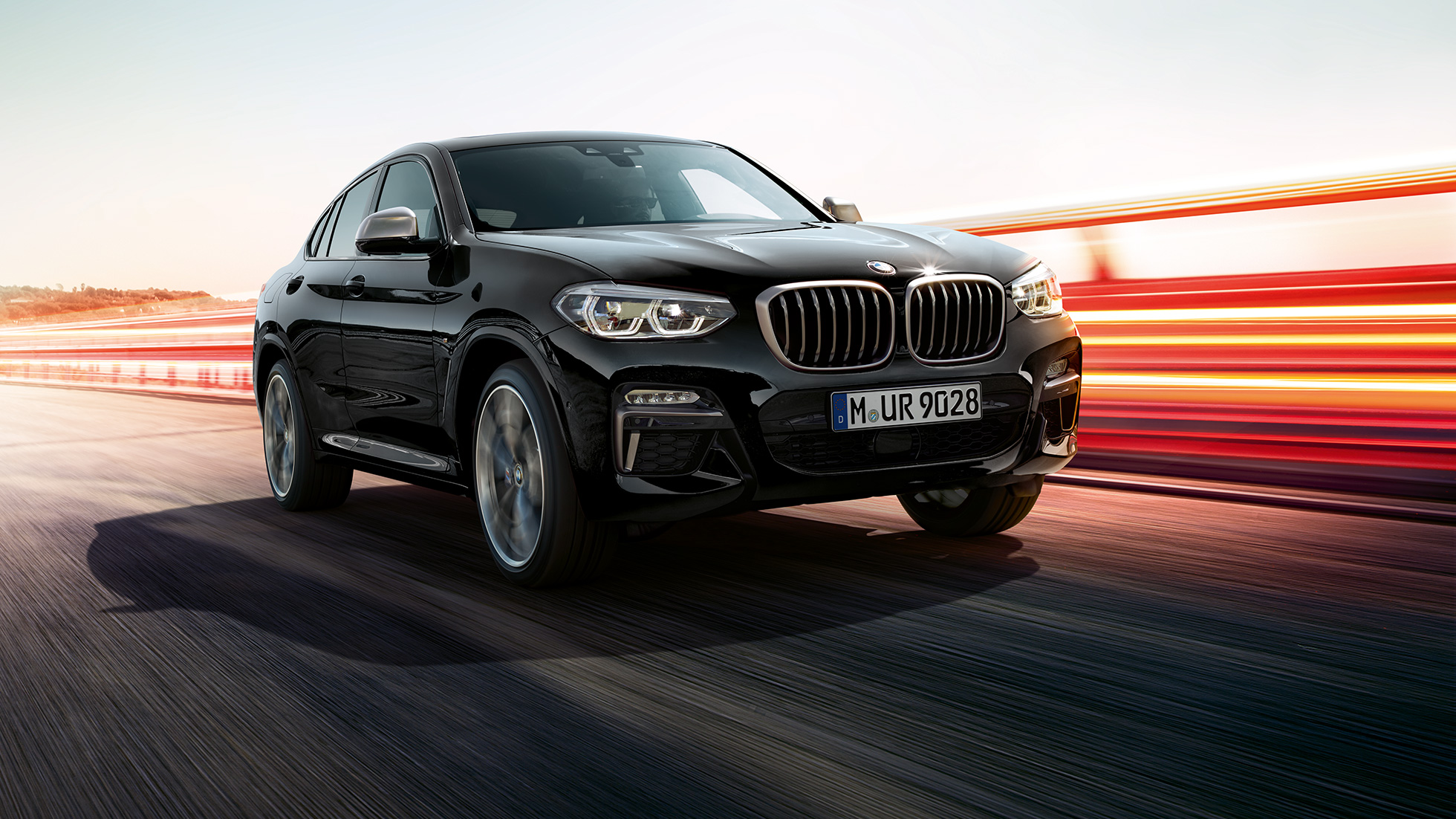 BMW X4 M40i és BMW X4 M40d, háromnegyedes elölnézet. Zafírfekete metálfényezésű BMW X4 M40i és BMW X4 M40d, kívülről, háromnegyedes elölnézetből, a bal oldal fénycsíkokkal.