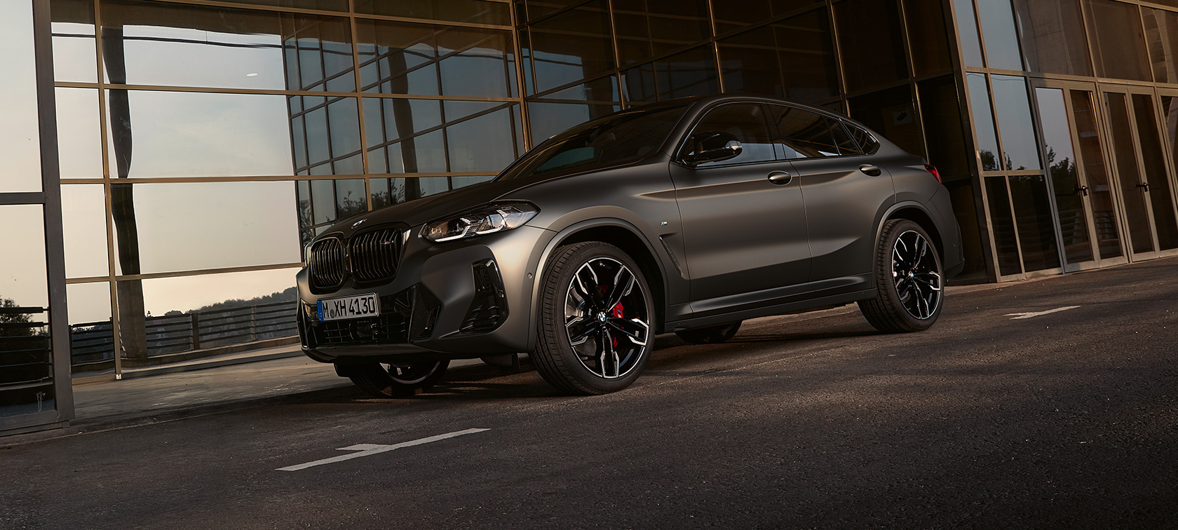 Rézsútos elölnézet, BMW X4 M40i, G02, LCI, 2021 Facelift BMW X4 M40i, G02 LCI, 2021 Facelift, egy üveghomlokzat előtt látható autó rézsútos elölnézetből