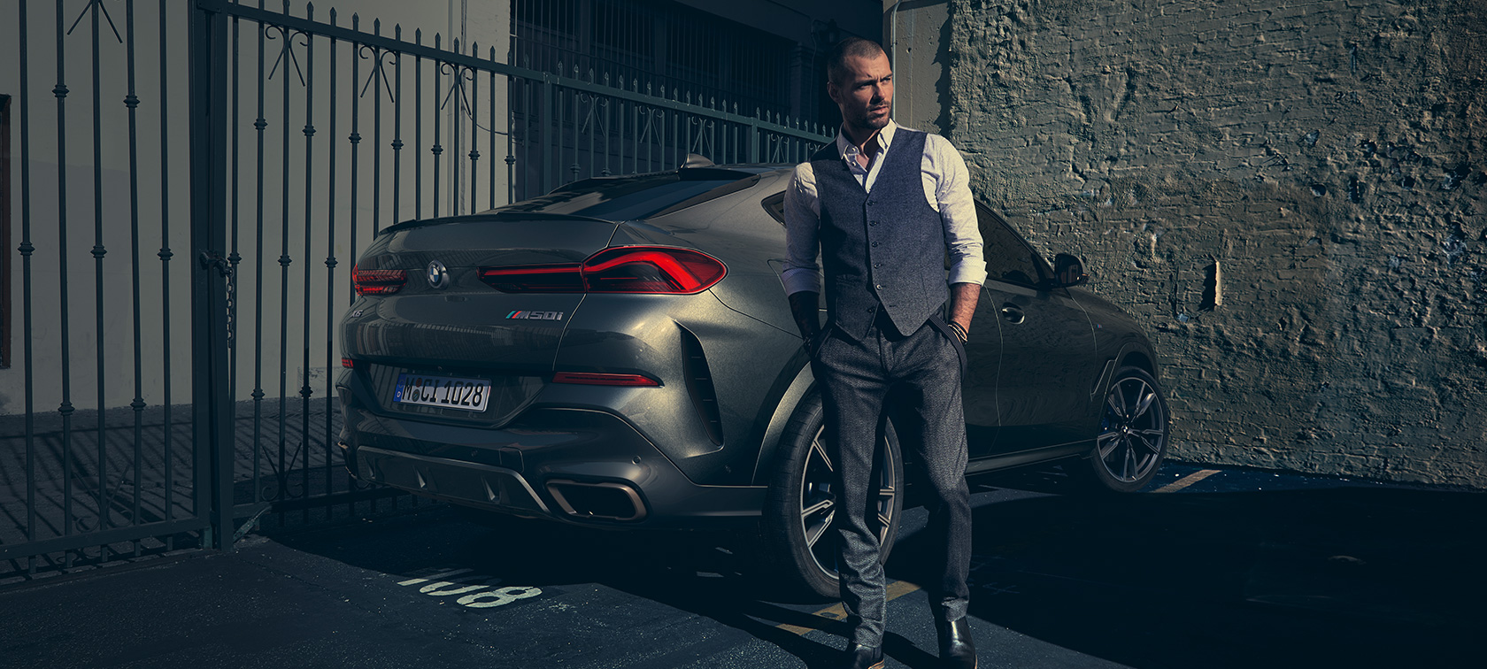 BMW X6 M50i, rézsútos hátulnézet, G06 Egy férfi áll egy BMW X6 M50i mellett, G06, 2018, SUV, rézsútos hátulnézet