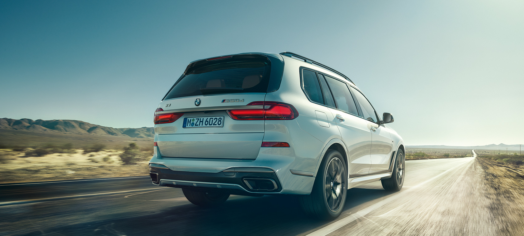 BMW X7 M50i, hátulnézet Egy üres autópályán haladó, Kristály fehér BMW X7 M50i (G07, 2019) hátulnézetből
