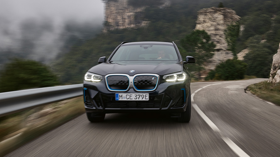 Egy mozgó autó elölnézetből, BMW iX3, G08, M Karbonfekete BMW iX3, G08, egy mozgó, M Karbonfekete jármű elölnézetből