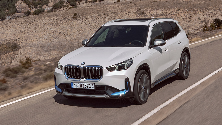 BMW iX1, U11, egy úton haladó, első generációs autó rézsútos elölnézetből BMW X sorozat, BMW iX1, U11, egy úton haladó, első generációs autó rézsútos elölnézetből