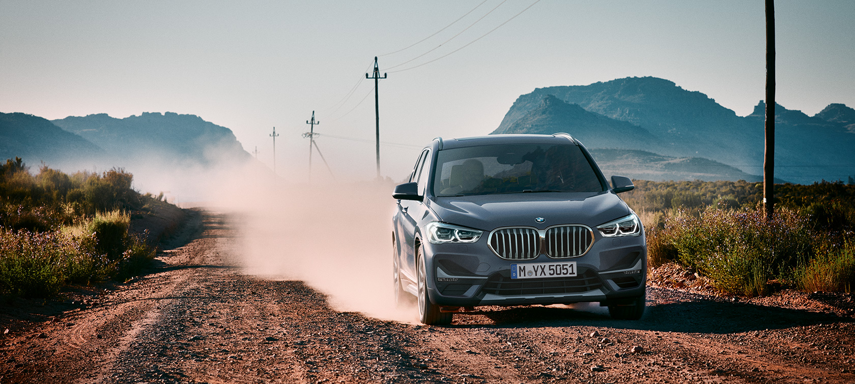BMW X1, háromnegyedes hátulnézet. BMW X1, az autó háromnegyedes hátulnézetből, hegyvidéki tájjal a háttérben.