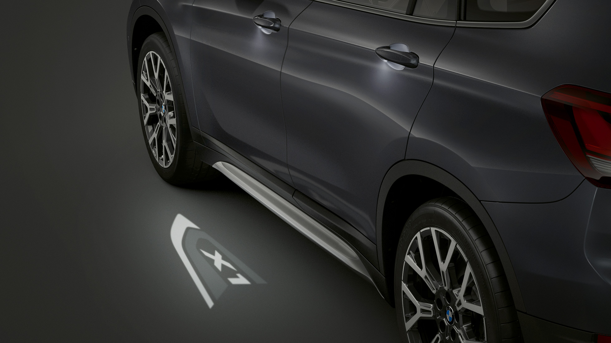 BMW X1, LED-es „X1” kivetítés. BMW X1, oldalnézet, középpontban a LED-es „X1” kivetítés.