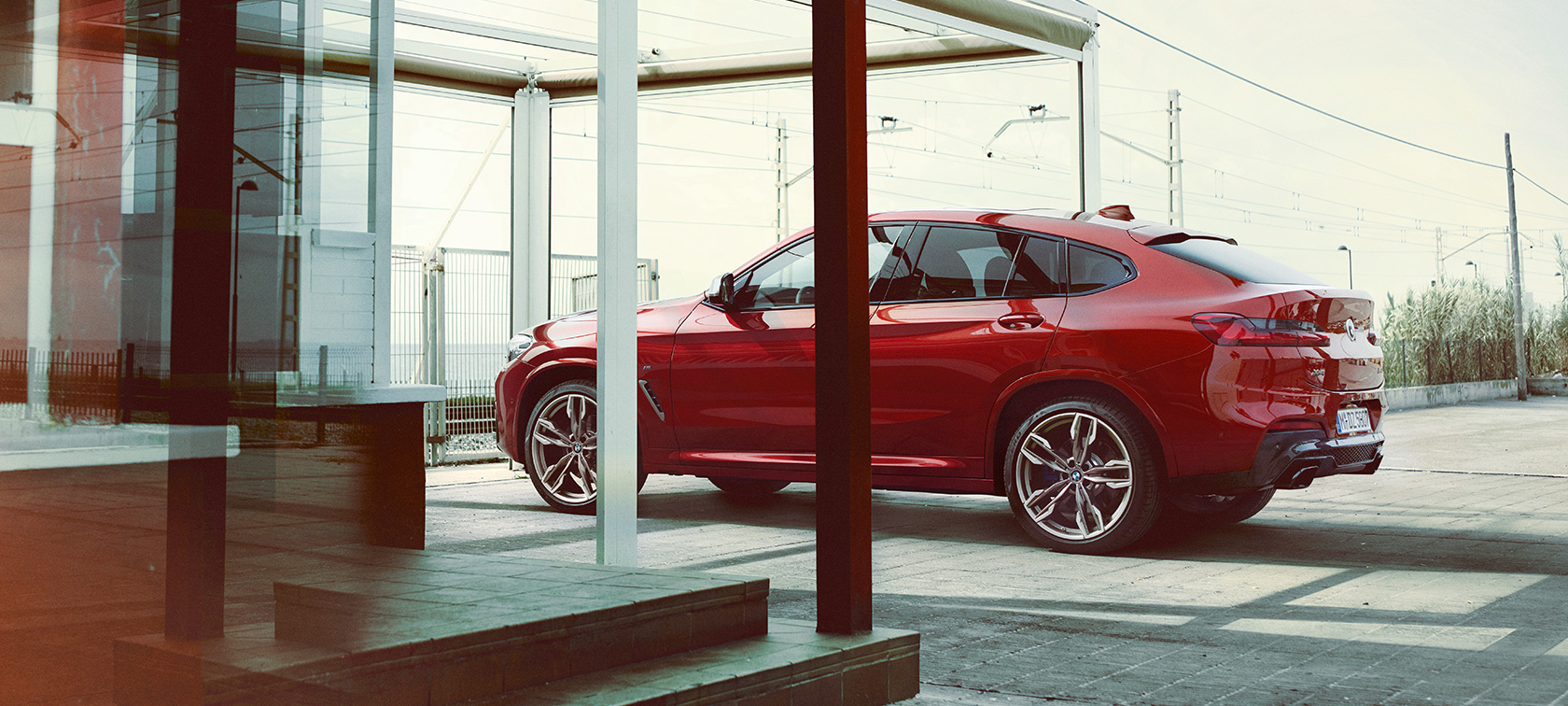 A BMX X4 oldalnézetből BMW X4 M40i, G02, 2018, Flamenco vörös briliáns hatással, a parkoló autó oldalnézetből