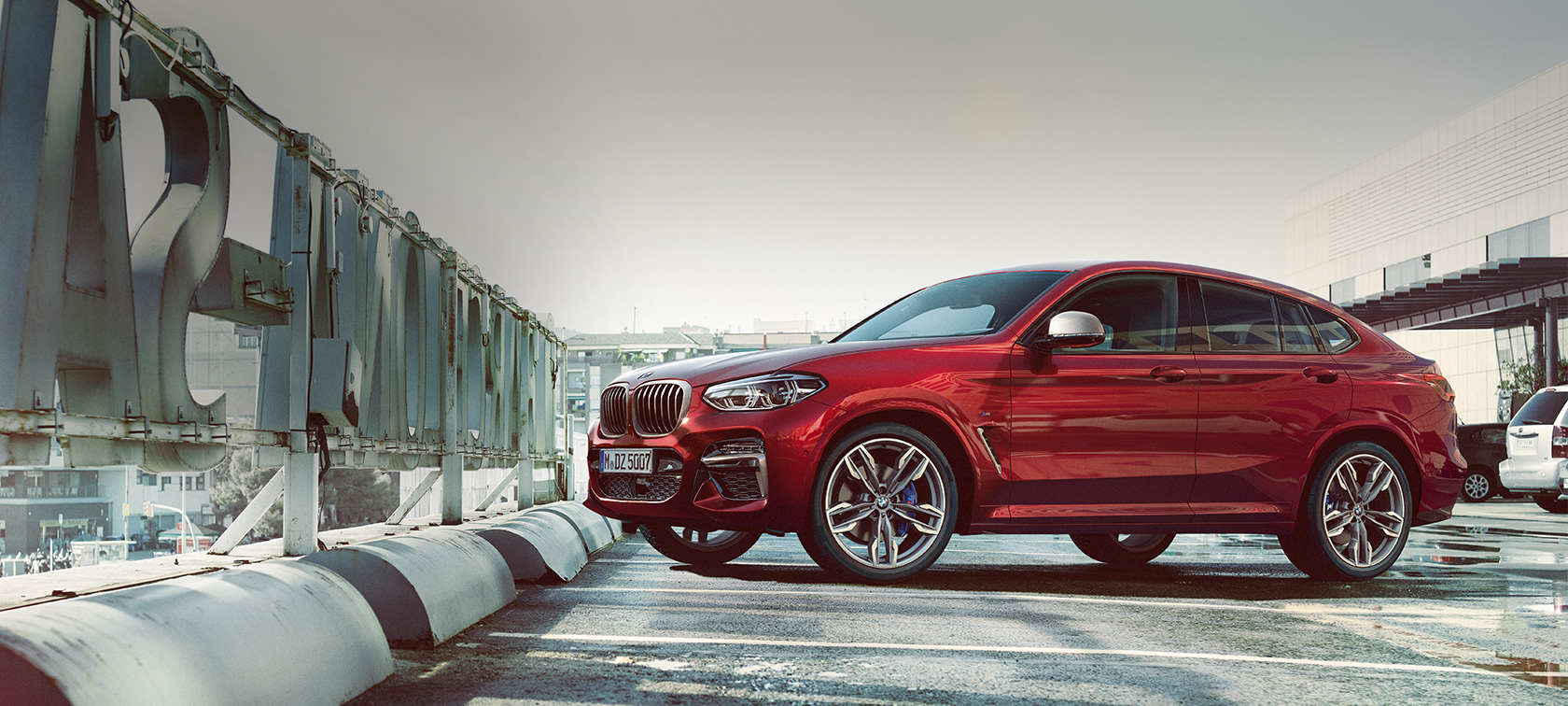 Egy parkoló BMW X4 oldalnézetből BMW X4 M40i, G02, 2018, Flamenco vörös briliáns hatással, egy parkolóhelyen álló autó oldalnézetből