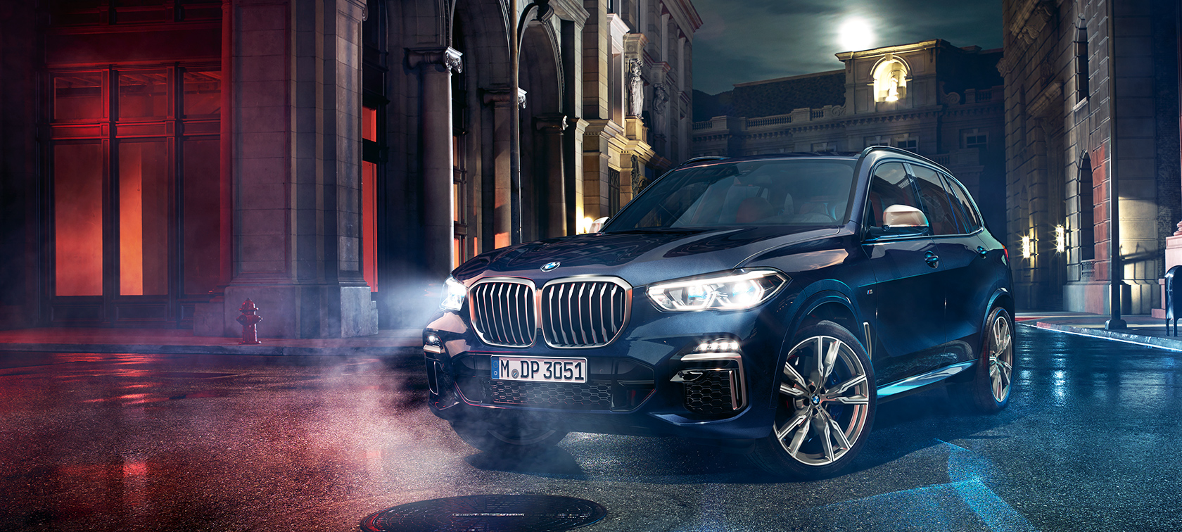 A BMW X5 M50d az úton A BMW X5 M50d éjszaka áll az úton, a háttérben a nagyvárossal