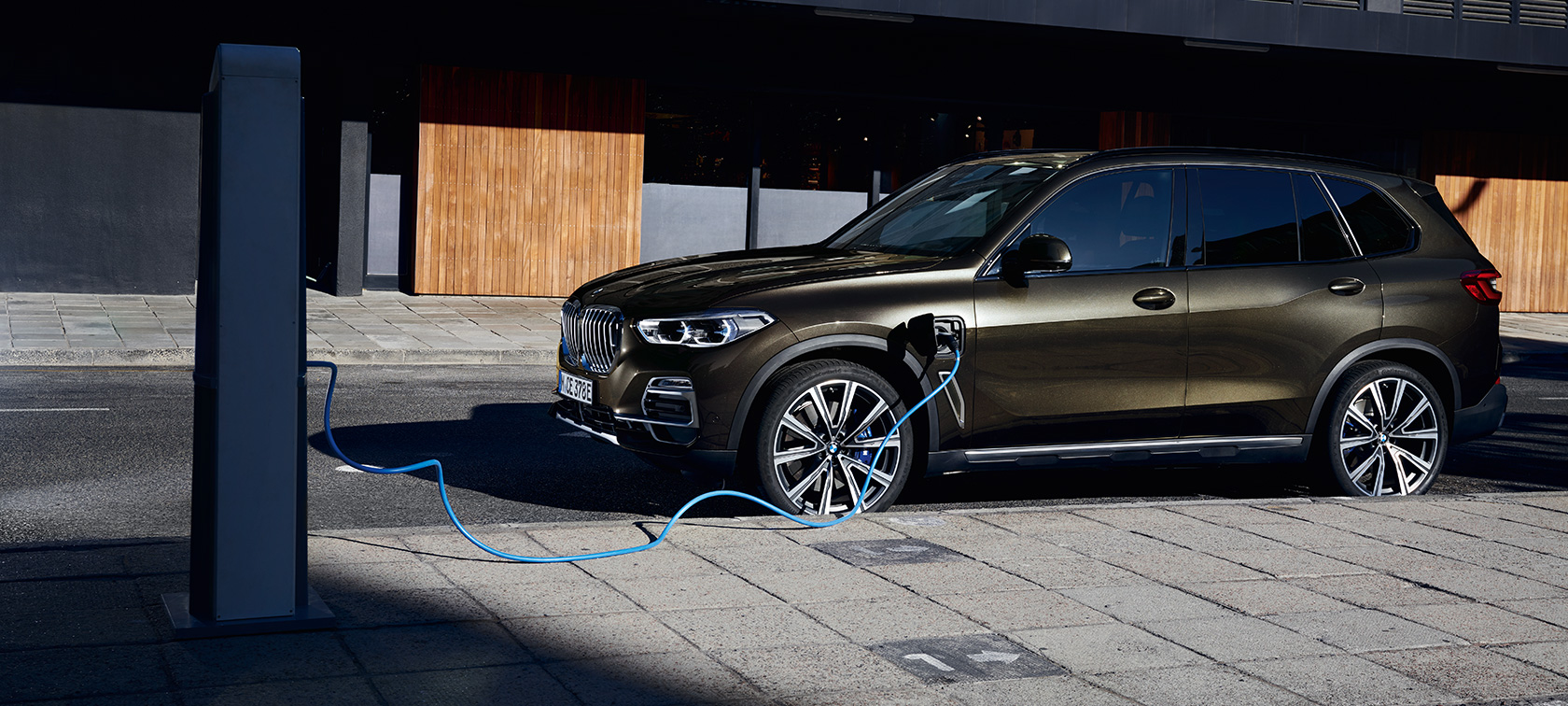 Plug-in hibrid, BMW X5 xDrive45e, G05, rézsútos oldalnézet Plug-in hibrid, BMW X5 xDrive45e, G05, egy töltés alatt álló autó rézsútos oldalnézetből