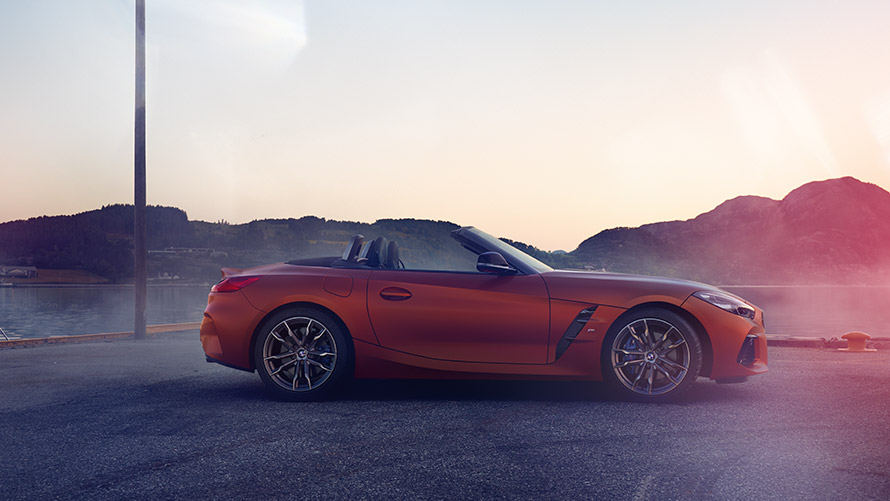 Egy narancsszínű BMW Z4 First Edition oldalnézetből Egy narancsszínű BMW Z4 First Edition oldalról, hegyvidéki tájjal a háttérben