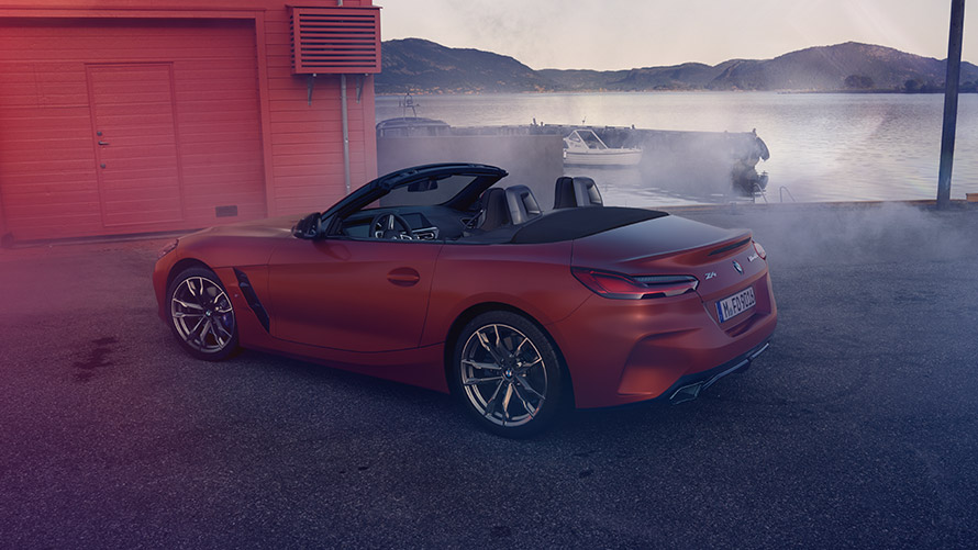 Egy narancsszínű BMW Z4 First Edition hátulról Egy narancsszínű BMW Z4 First Edition hátulról, egy pirosra festett parti ház előtt