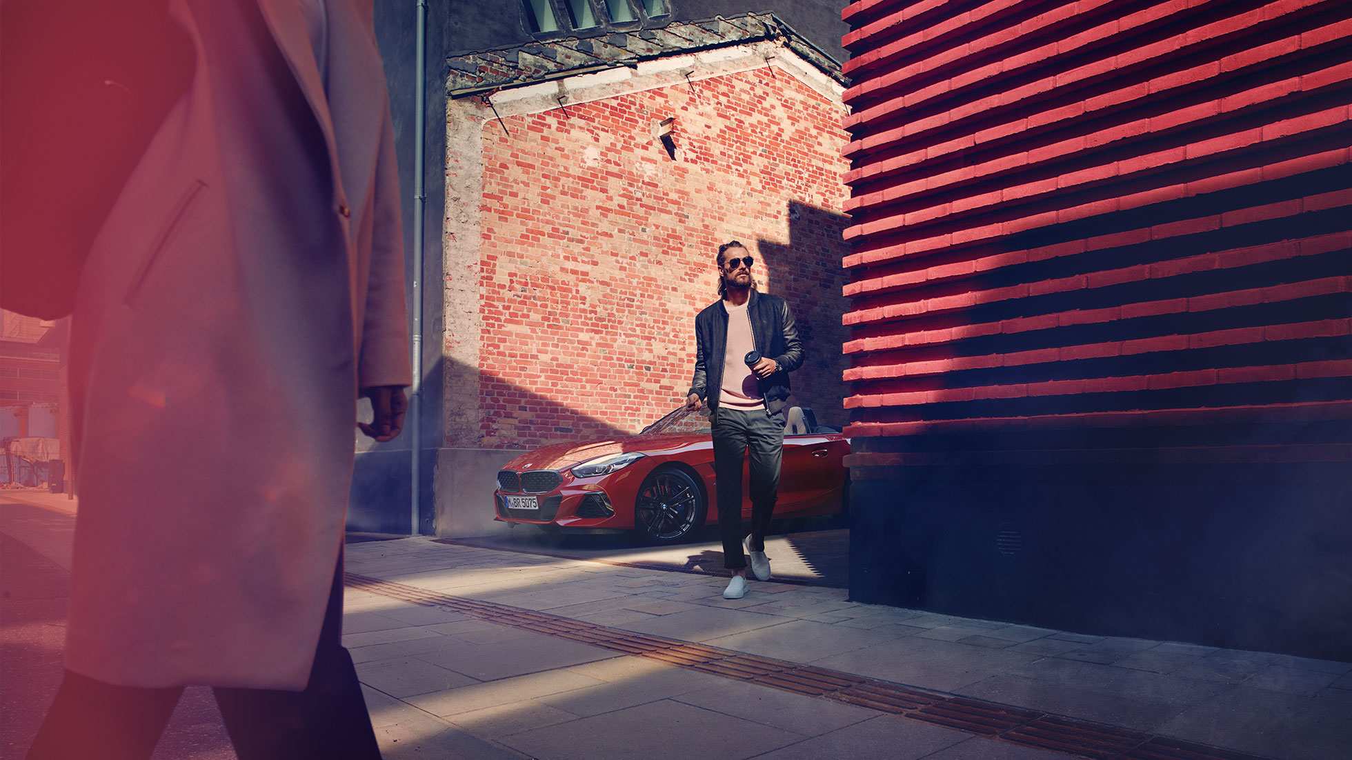 A BMW Z4 Roadster egy mellékutcában Egy férfi egy mellékutcában, a BMW Z4 Roadster előtt
