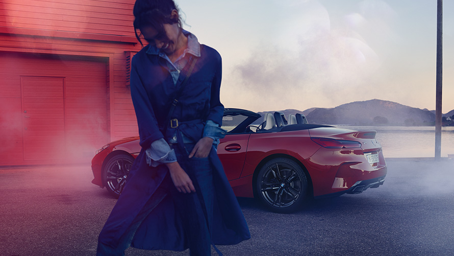 BMW Z4 M40i Roadster, G29, egy autó nyitott vászontetővel BMW Z4 M40i Roadster, G29, egy nyitott vászontetős, rézsútos hátulnézetből látható autó egy nővel az előtérben