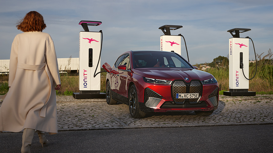 BMW Speciális Értékesítés, Fenntarthatóság, Áttekintés, BMW Charging megoldások, egy töltőállomáson álló BMW, a háttérben egy nővel