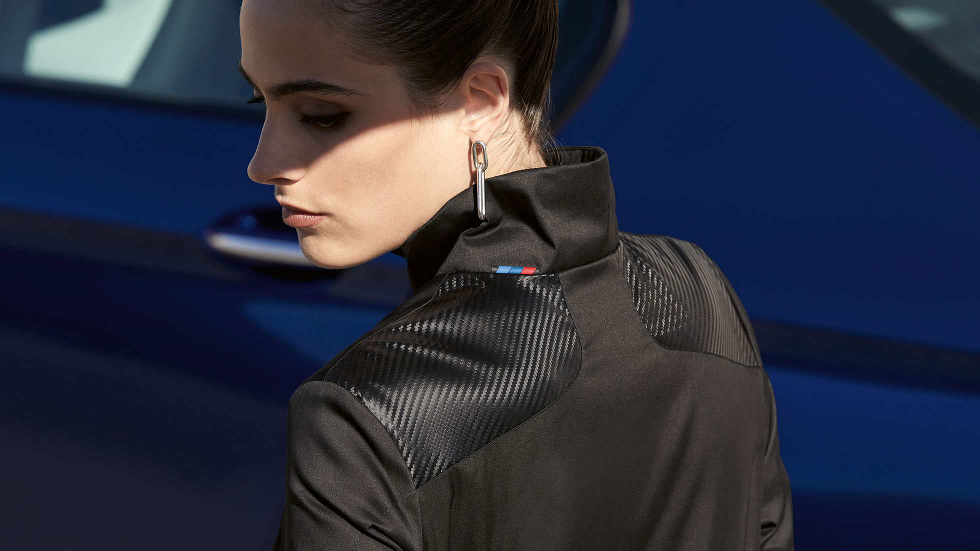 BMW M női dzseki. A képen látható nő egy, a BMW M kollekcióba látható BMW M női dzsekit visel. Az anyagmix részlete.