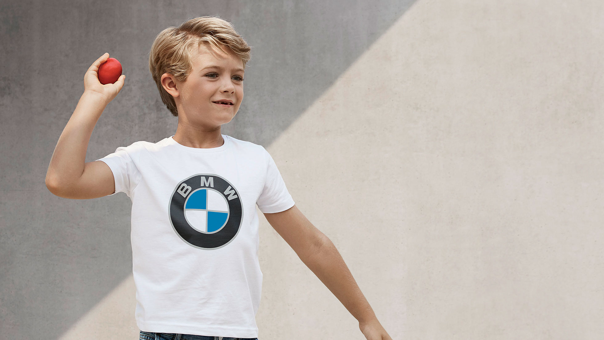 BMW Kids Kollekció. Egy fiú a BMW Kids Kollekcióba tartozó termékeket viseli.
