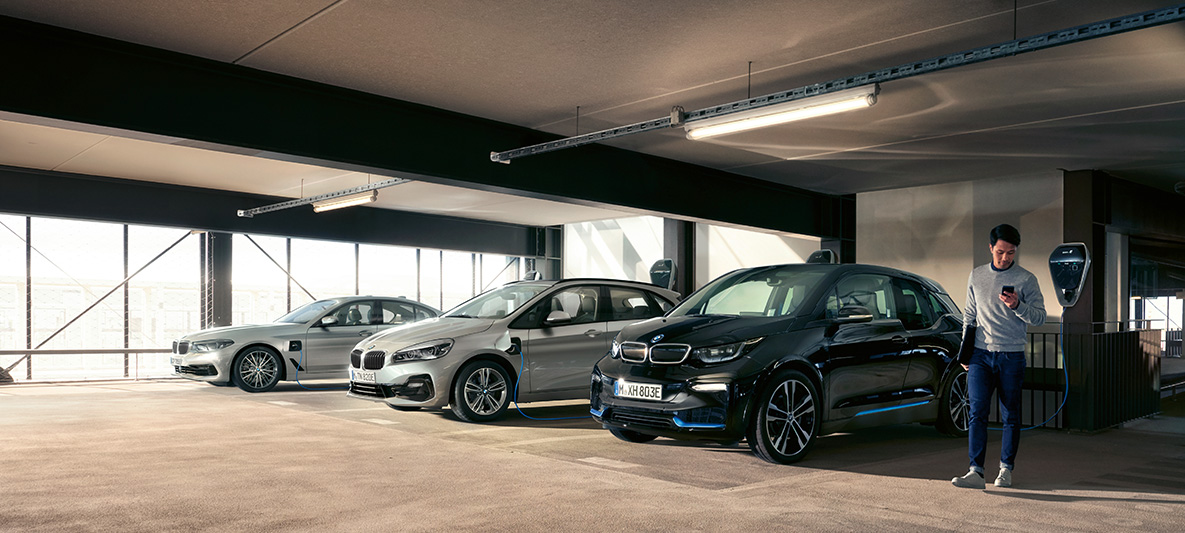 BMW elektromos autók és hibrid járművek egy töltőállomáson BMW adókedvezmények, BMW elektromos autók és hibrid járművek, egy férfi egy töltőállomáson