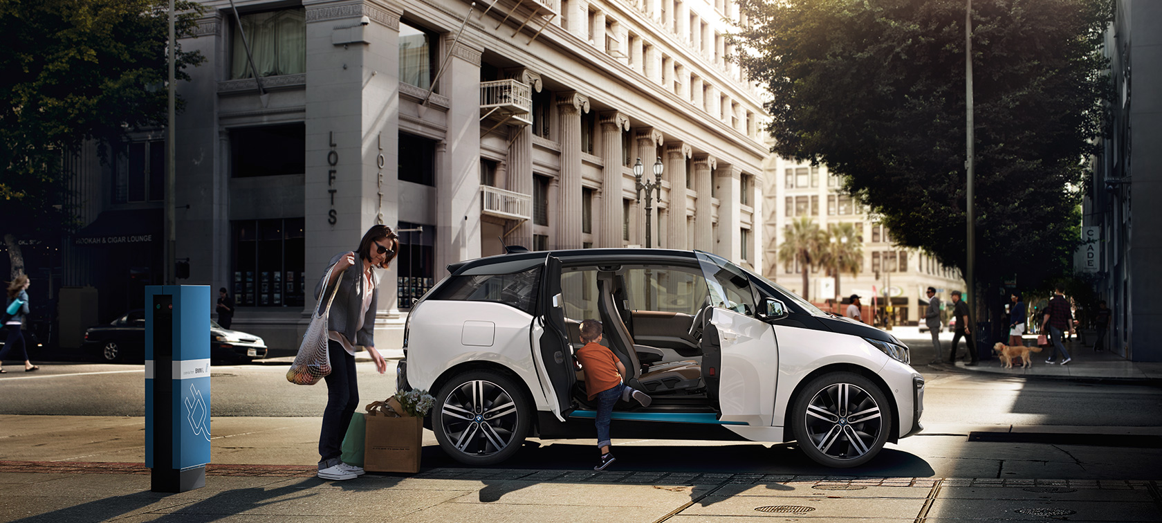 Egy BMW i3 városi városi környezetben BMW modellkínálat, egy BMW i3 városi környezetben egy nő és egy gyermek társaságában