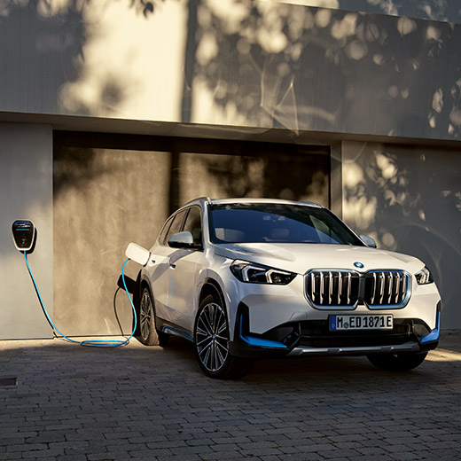 BMW iX1, U11 BEV, töltés egy garázs előtt