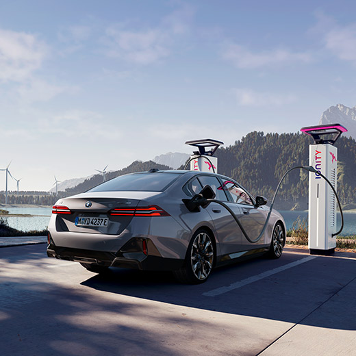 BMW i5 eDrive40, G60, egy töltőállomásnál tartózkodó autó, a háttérben egy tó