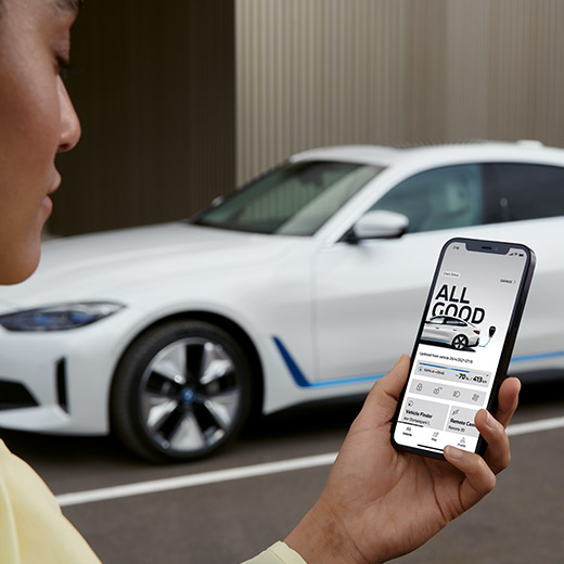 Connected Charging a My BMW appban, BMW i4, G26, egy autó egy személlyel az előtérben