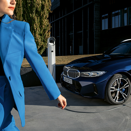 Egy töltés alatt álló BMW, amely előtt egy nő sétál el