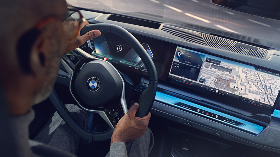 BMW belső tér, egy férfi a BMW Operating System 8.5 felületét mutató kijelzőt nézi BMW belső tér, egy férfi a BMW Operating System 8.5 felületét mutató kijelzőt nézi