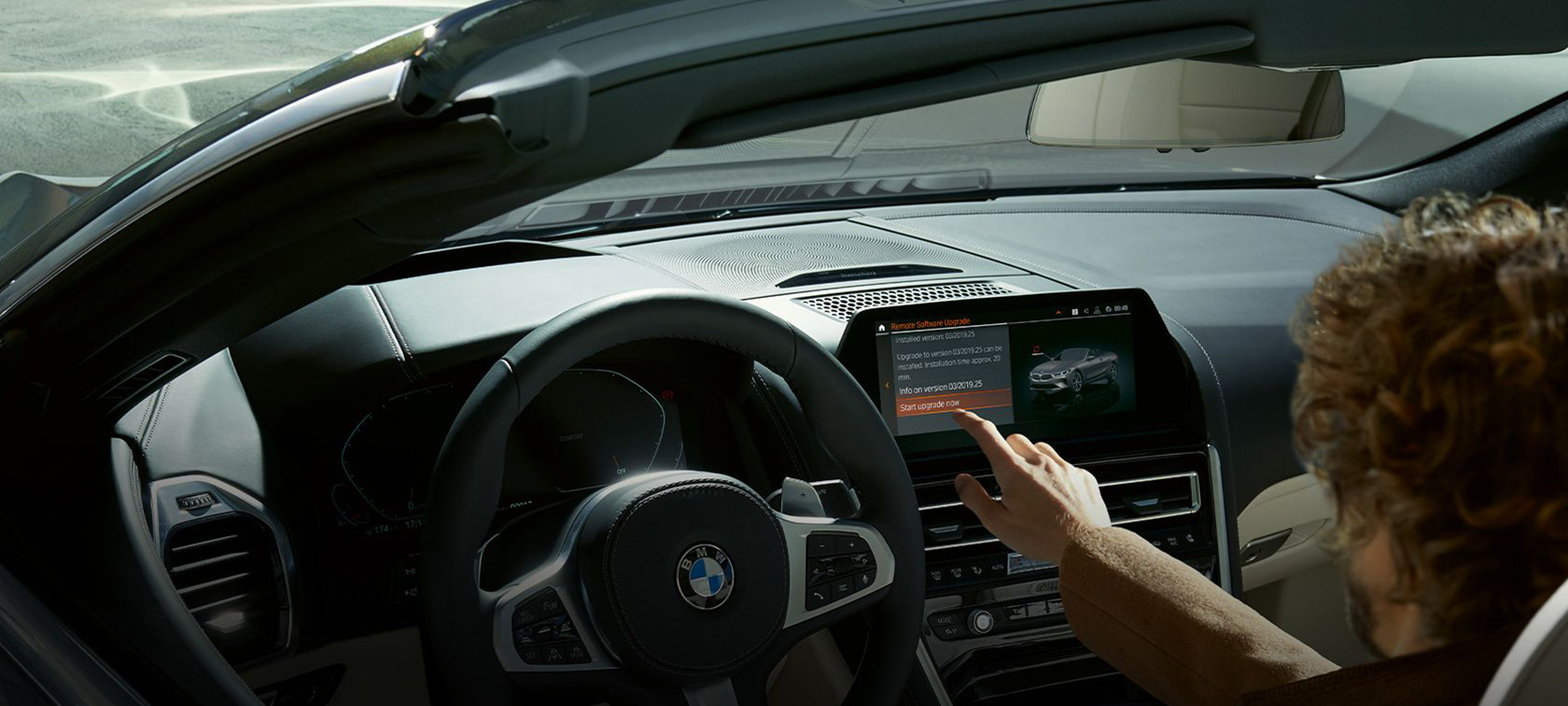 BMW távoli szoftverfrissítés Egy, a BMW-jében ülő férfi elindítja a BMW távoli szoftverfrissítést