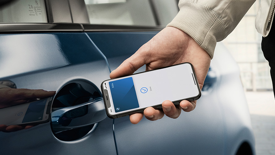 Digitális kulcs Egy férfi az okostelefonra telepített Digitális kulccsal nyitja a BMW-t