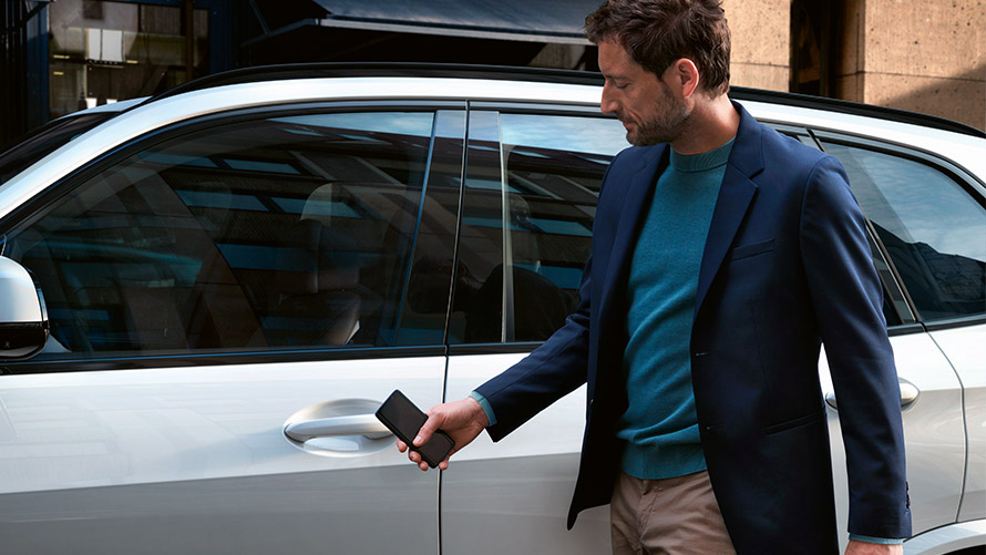 Digitális kulcs Egy férfi az okostelefonra telepített Digitális kulccsal nyitja a BMW-t