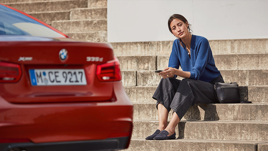 Service & Roadside Assistance Egy, a BMW-je előtt ülő nő a Service & Roadside Assistance funkciót használja