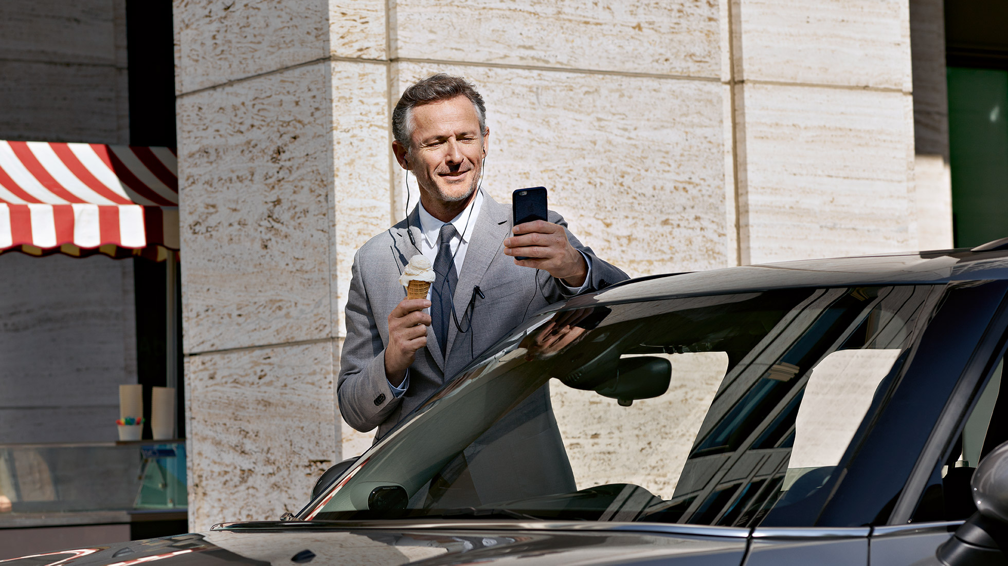BMW Corporate Aftersales, control finances BMW Corporate Aftersales: Egy férfi jégkrémet eszik, miközben pénzügyeit okostelefonján intézi