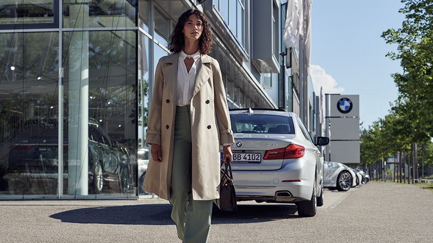 BMW Service Inclusive Egy nő áll egy BMW márkakereskedés előtt