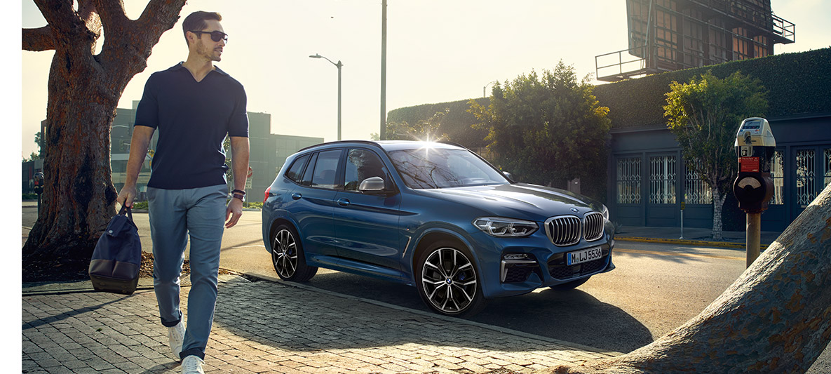 Egy napszemüveges férfi áll egy kék BMW előtt Egy napszemüveges férfi áll egy kék BMW előtt