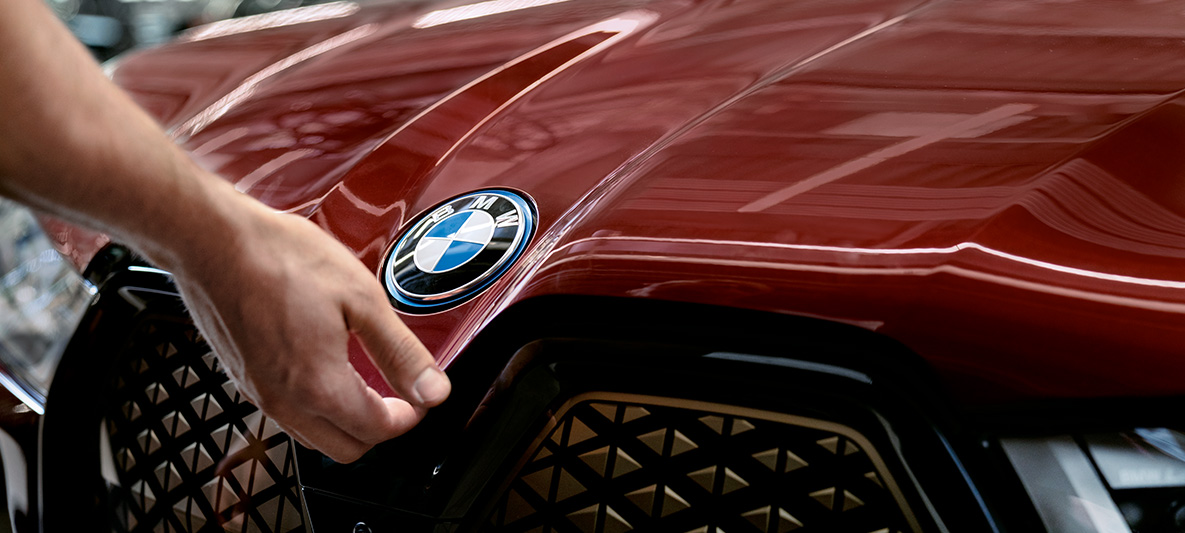 BMW járműátvizsgálás és karbantartás BMW járműátvizsgálás és karbantartás, egy BMW motorháztetőjén nyugvó kéz