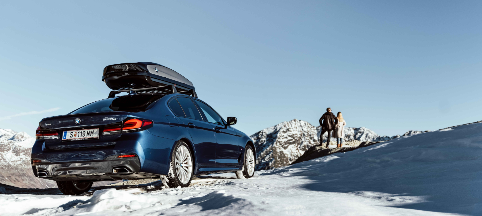 Eredeti BMW tartozékok és BMW Service szolgáltatások őszre és télre Egy nő és egy férfi nevet a hóban a tüskés gumikon