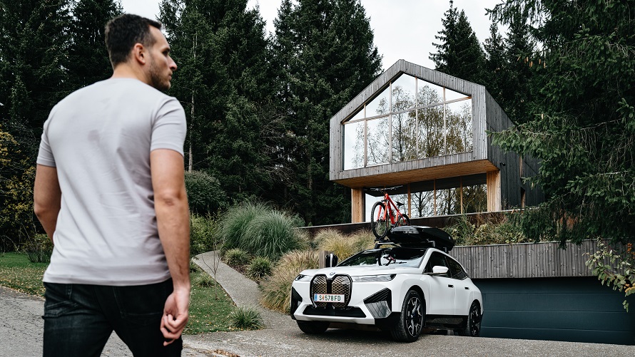 Egy férfi egy ház előtt álló BMW iX-hez megy. Egy férfi egy ház előtt álló BMW iX-hez megy.