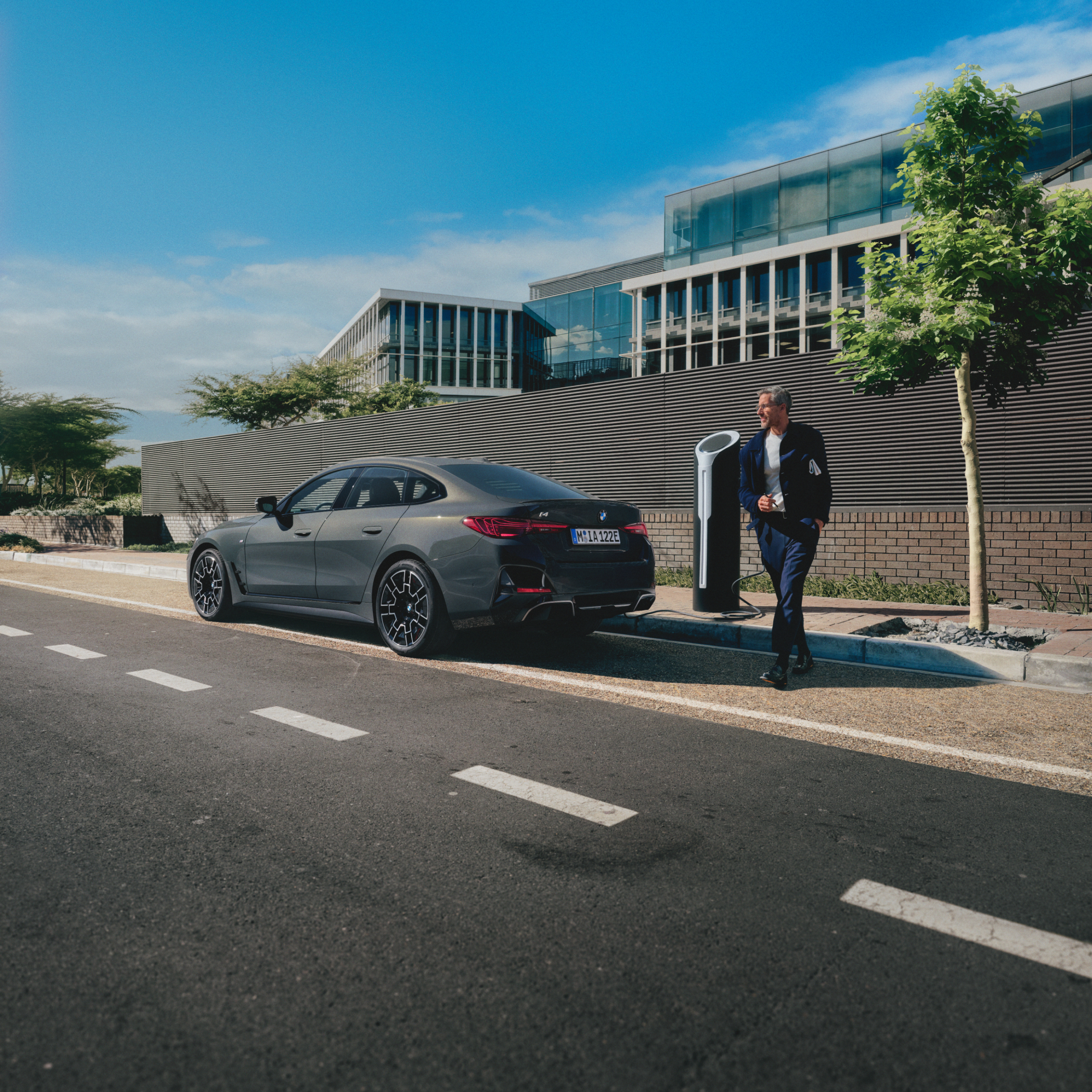 Egy töltődő BMW mögött álló személy az út szélén