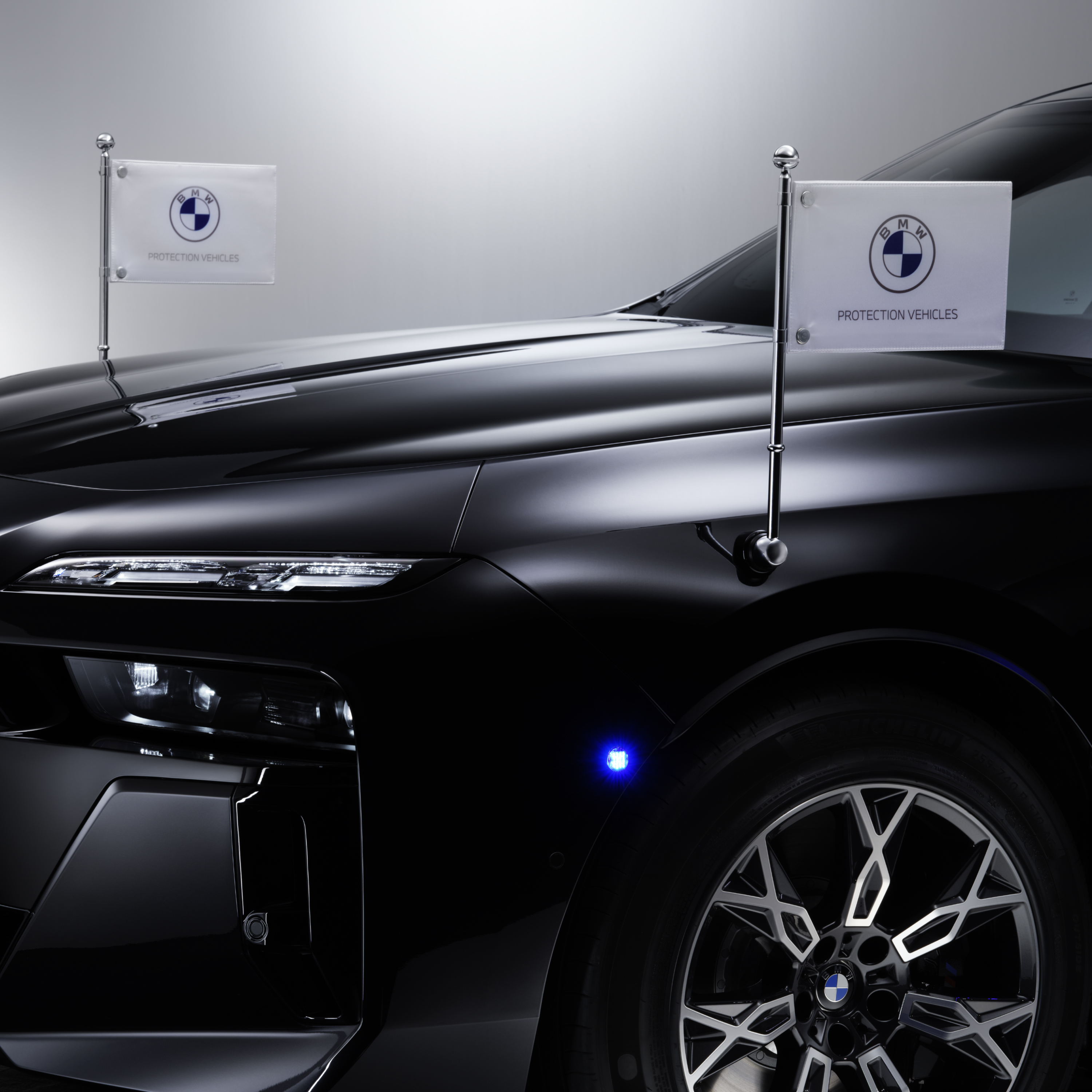 Egy BMW közeli képe elöl két zászlótartóval