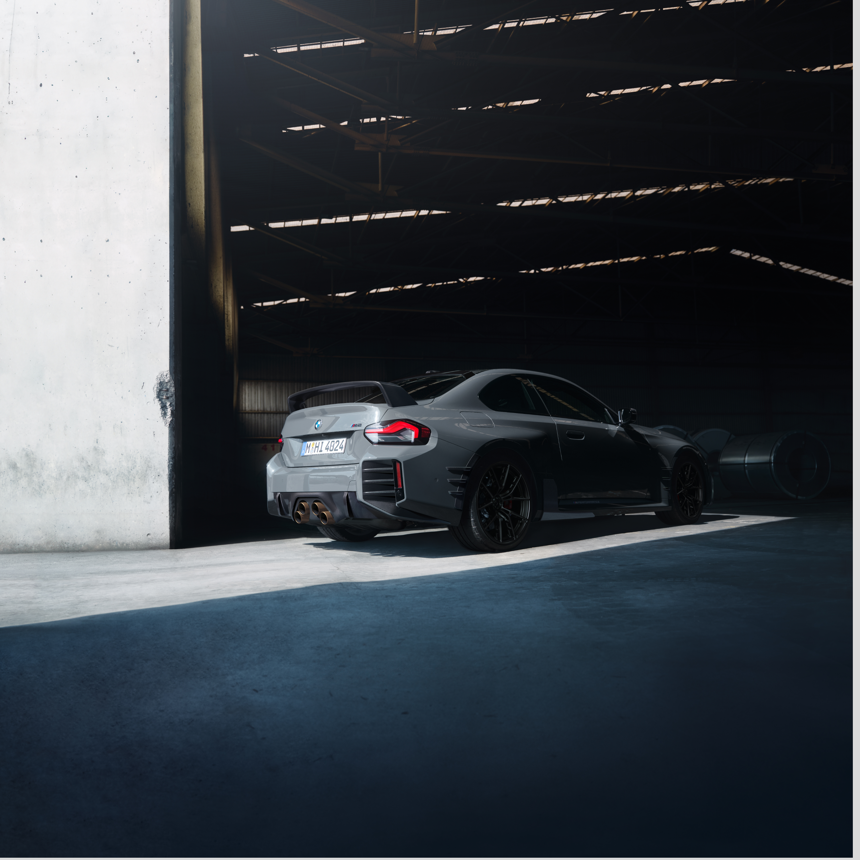 Egy BMW egy nagy csarnok kapujánál áll