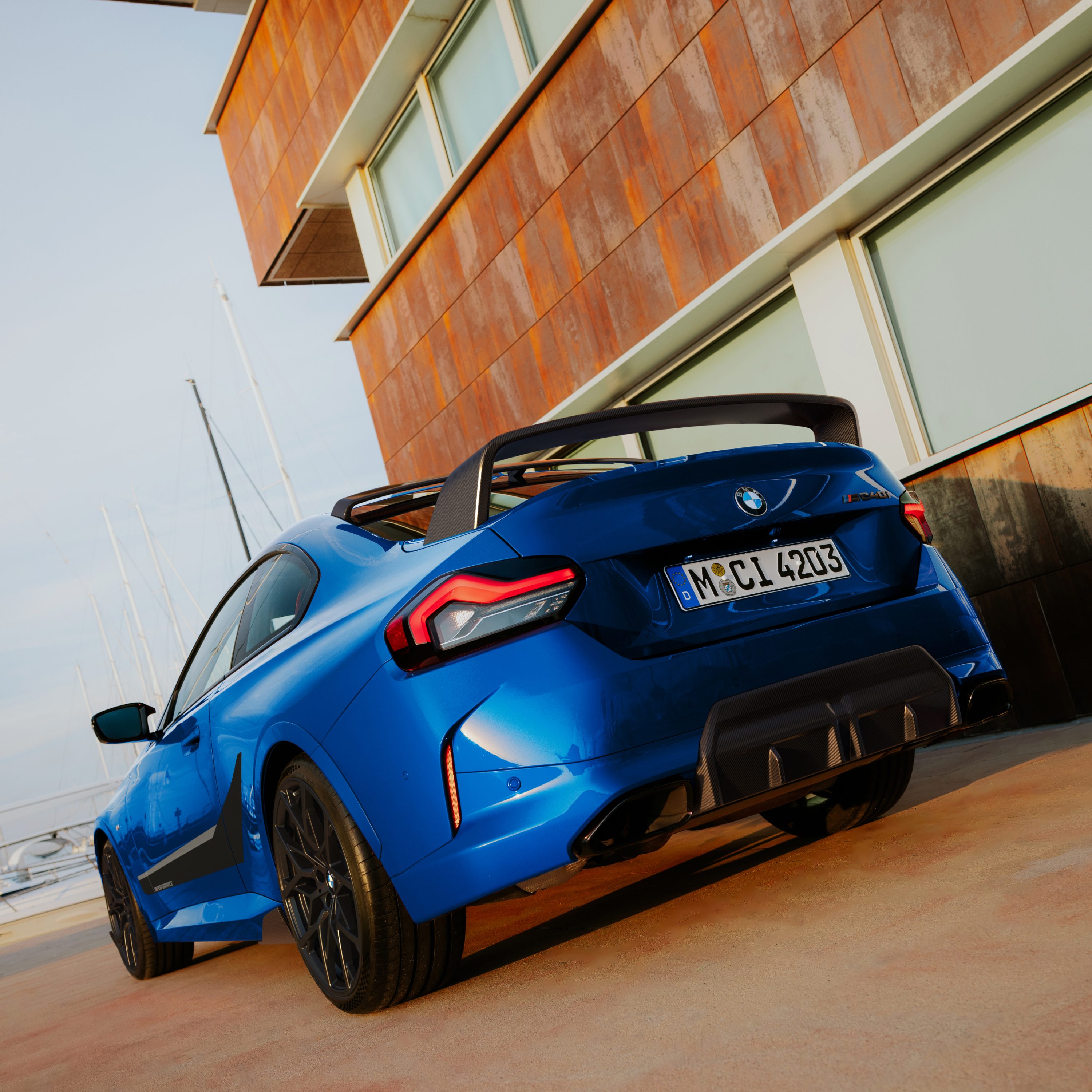 Egy BMW M Performance hátsó spoilerrel felszerelt modell parkol egy ház előtt