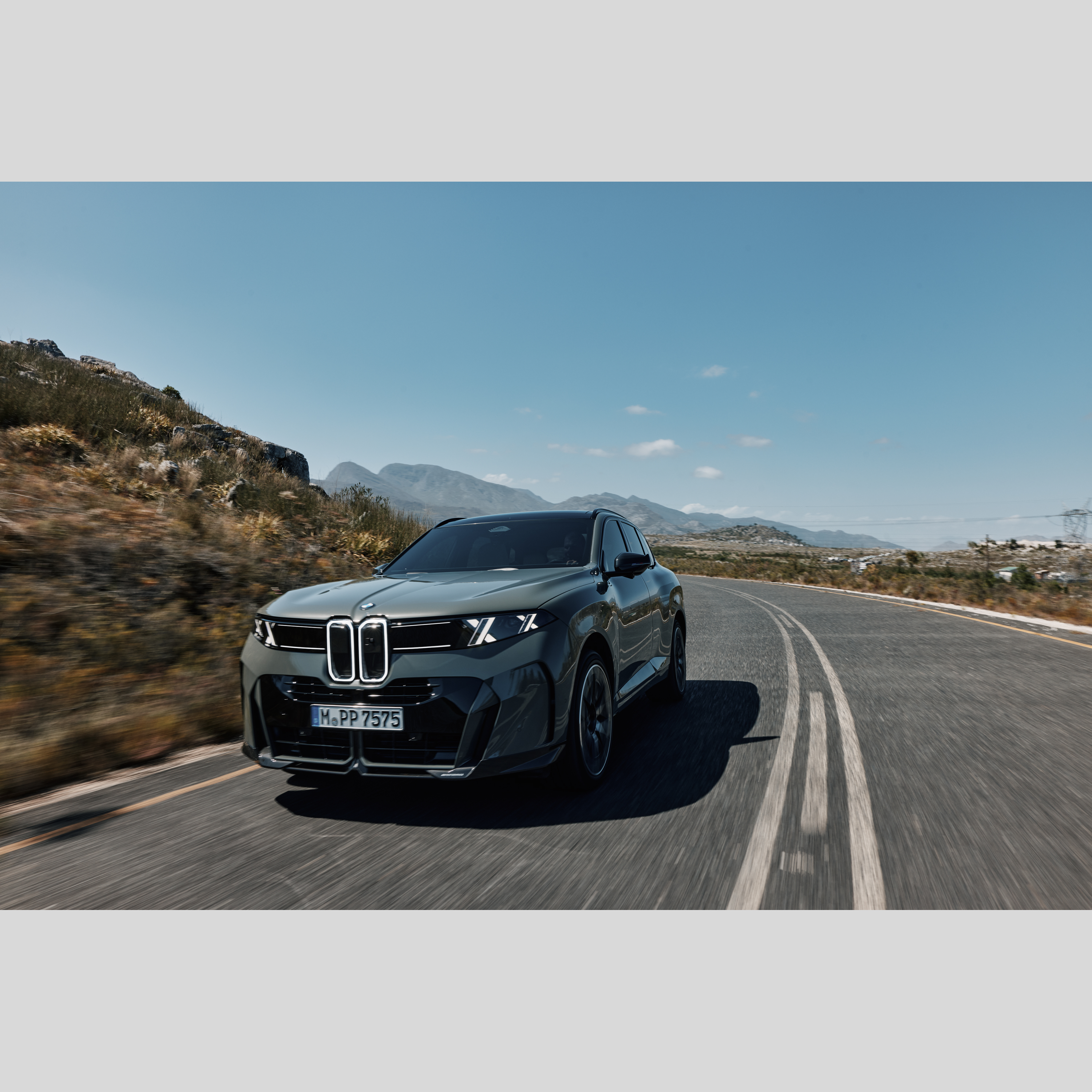 A BMW iX5 kanyargós hegyi úton halad a naplementében