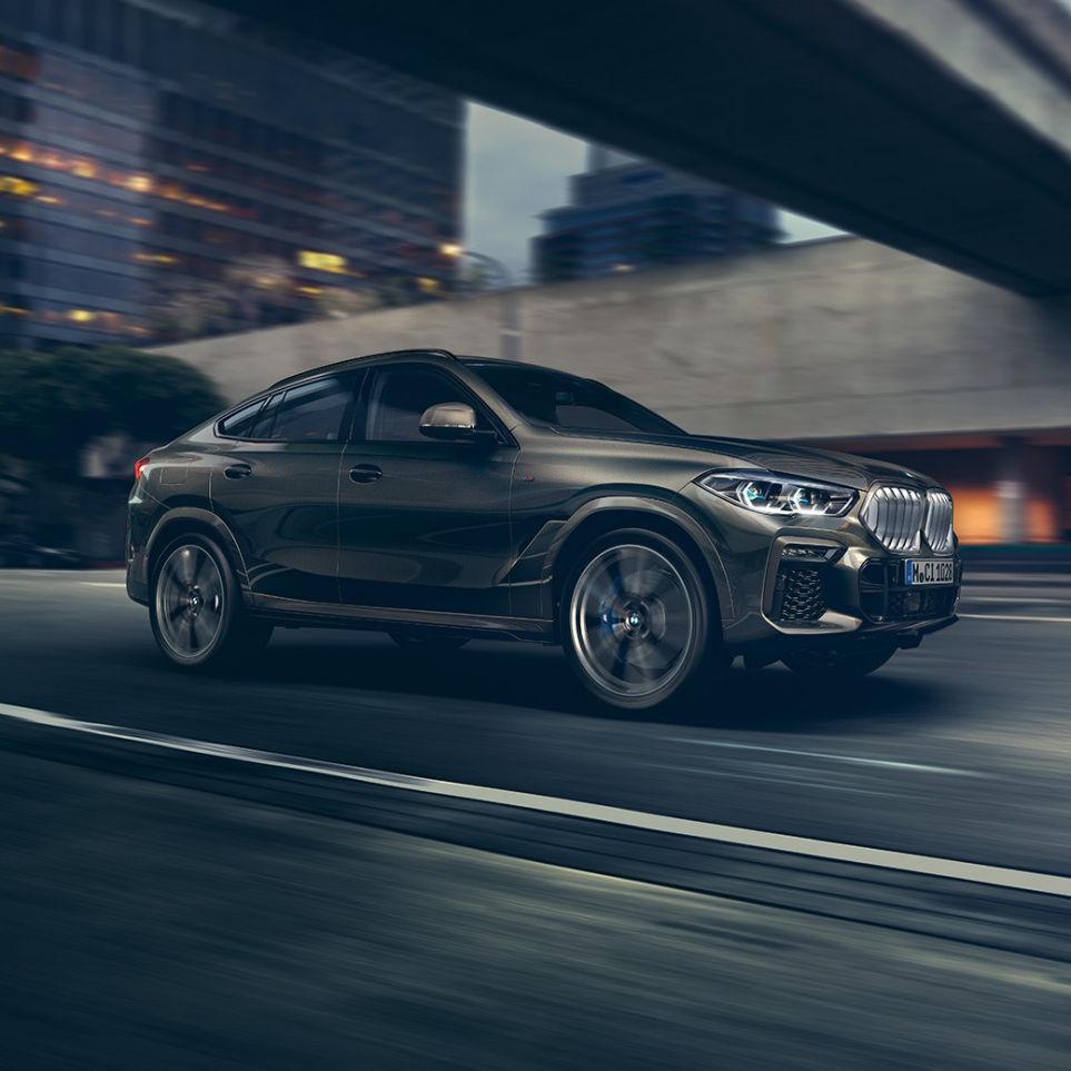 BMW X6 mozgás közben. Egy mozgó BMW X6 rézsútos elölnézetből, városi környezetben.